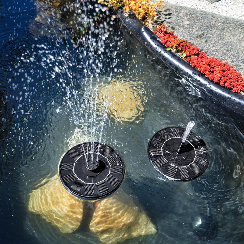 Fontäner sprayar vatten i liten damm i trädgård i solen bland vatten